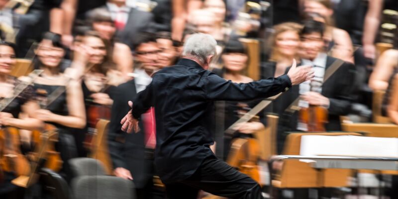 Rear view of a conductor in front of an orchestra